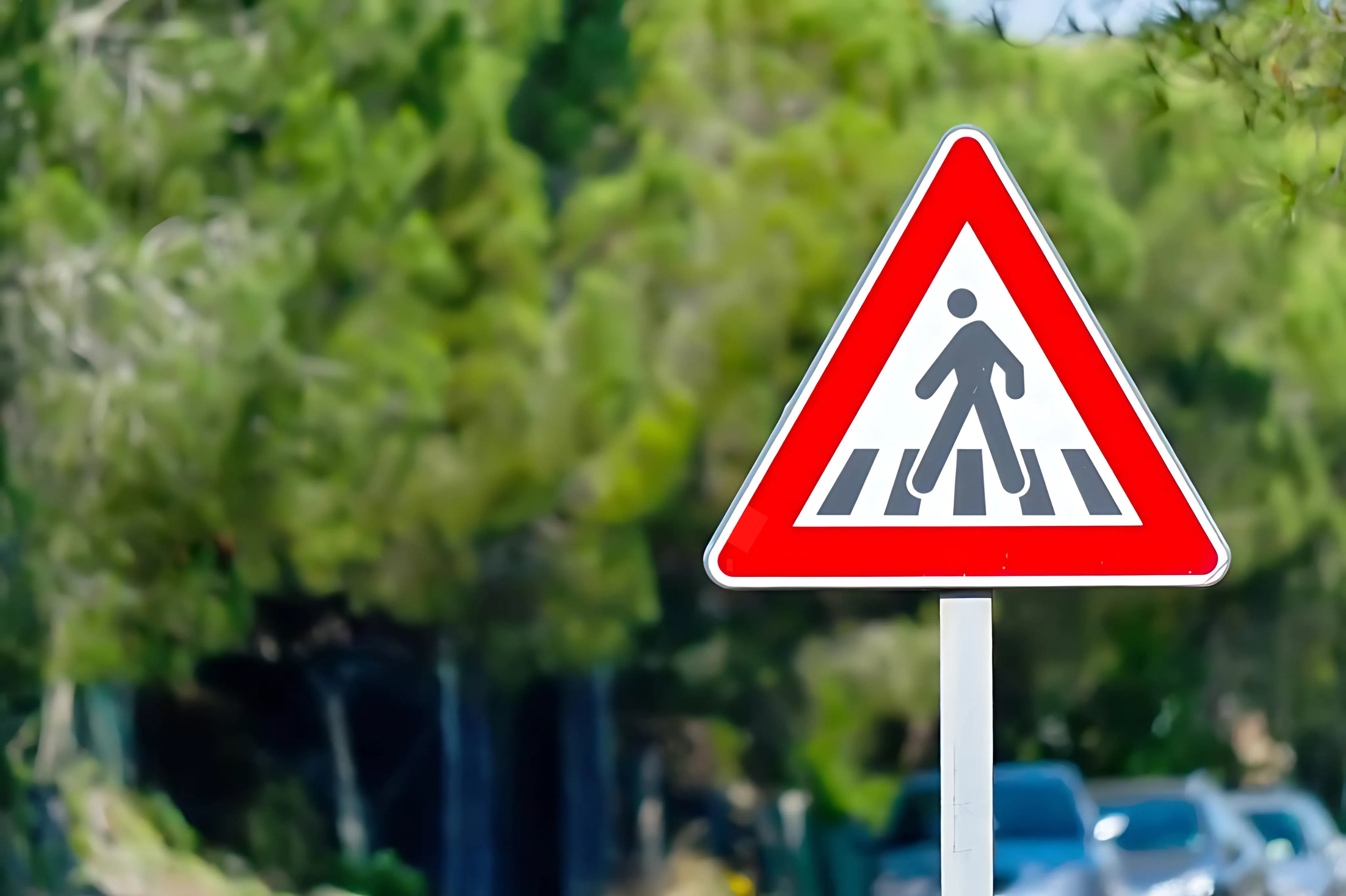 Un cartello stradale che raffigura il segnale di pericolo attraversamento pedoni.